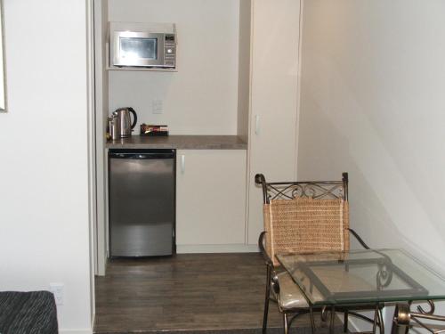 a small kitchen with a table and a microwave at Greyfriars Motel in Greytown