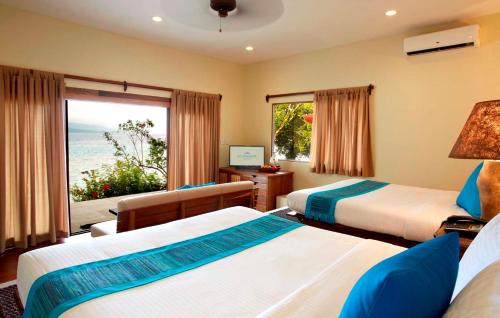 a bedroom with two beds and a view of the ocean at Bluewater Sumilon Island Resort in Sumilon Island