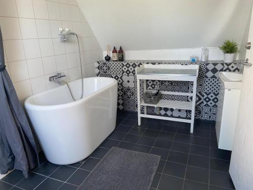 a bathroom with a white tub and black tiles at Kungshagagård in Höllviken