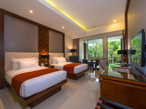 a hotel room with two beds and a desk at Puri Asri Hotel & Resort in Magelang