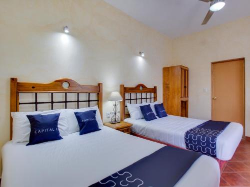 two beds in a bedroom with blue and white pillows at Hotel Valle De Oaxaca in Oaxaca City