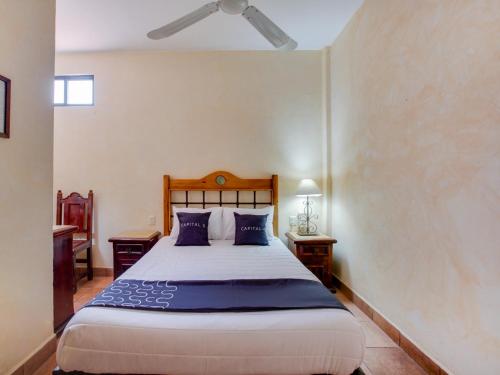 a bedroom with a large bed with blue pillows at Hotel Valle De Oaxaca in Oaxaca City