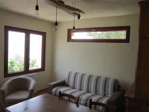 a living room with a couch and a table and two windows at casa indipendente "IL SOLE DELLE GRIGNE" in Bellagio