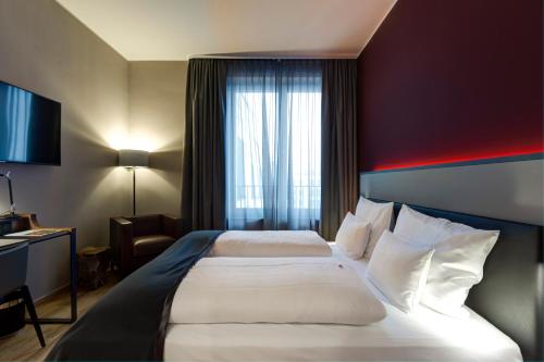 um quarto de hotel com uma cama grande e uma janela em Qube Hotel Bahnstadt em Heidelberg