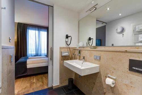 een badkamer met een wastafel en een spiegel bij Qube Hotel Bahnstadt in Heidelberg