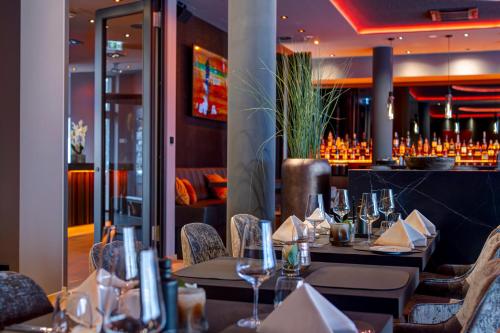 a restaurant with tables and chairs with wine glasses at Qube Hotel Bahnstadt in Heidelberg