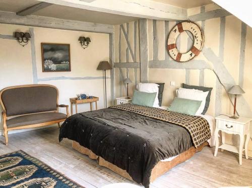 a bedroom with a large bed and a chair at La Cour Sainte Catherine demeure de charme in Honfleur