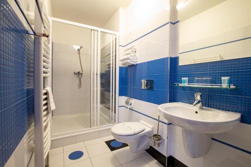 uma casa de banho azul e branca com um lavatório e um WC em Greensgate Hotel Dýšina em Horomyslice