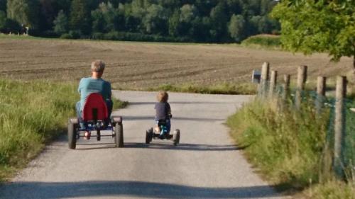 a man and a child riding on toy cars down a road at Niederauer Hof in Neubeuern