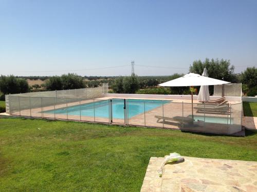 a swimming pool with an umbrella and a table with an umbrella at Monte da Boavista - Country family house in Alter do Chão