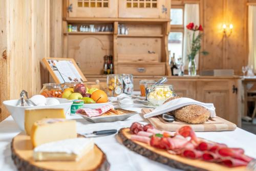 uma mesa com queijo e frutas e outros alimentos em Hotel Veduta em Cinuos-Chel