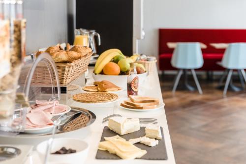 a table topped with cheese and bread and fruit at Grand Hôtel Clichy Paris in Clichy