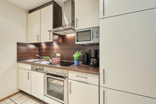 una cocina con armarios blancos y electrodomésticos de acero inoxidable en Haus Seemuschel _ Fewo 2 en Cuxhaven
