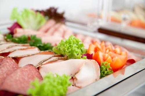 a tray of food with meat and vegetables on display at Qube Hotel Bahnstadt in Heidelberg