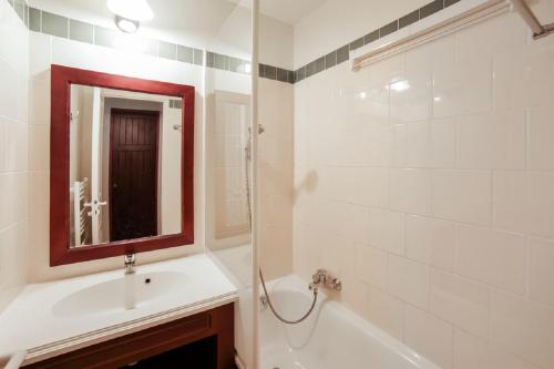 a bathroom with a sink and a tub and a mirror at Residence Le Domaine de Gascogne - maeva Home in Biscarrosse
