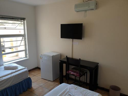 a room with two beds and a television on the wall at Amakaya Backpackers Travellers Accommodation in Plettenberg Bay
