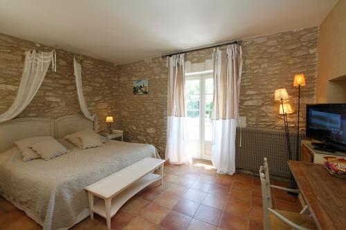 a bedroom with a large bed and a television at Mas des Carassins in Saint-Rémy-de-Provence