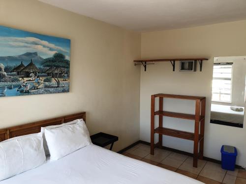 a bedroom with a bed and a painting on the wall at Amakaya Backpackers Travellers Accommodation in Plettenberg Bay