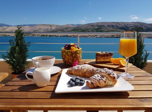 une table avec une assiette de nourriture et un verre de jus d'orange dans l'établissement Boutique Villa Revelin, à Pag