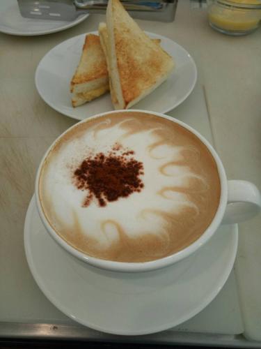 a cup of coffee sitting on a plate with toast at Casa Blanca Boutique Hotel - SHA Plus in Phuket Town