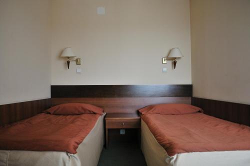 a room with two beds and a desk with lamps at Plaza Hotel in Varna City