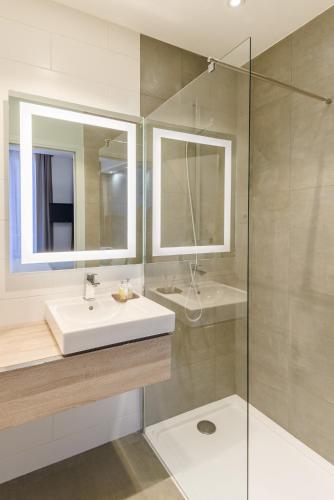 a bathroom with a sink and a glass shower at Grand Hôtel Clichy Paris in Clichy