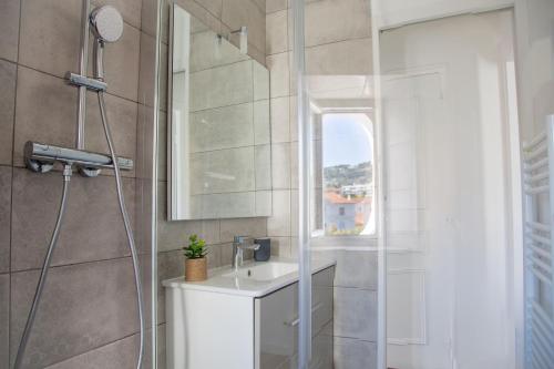 une salle de bain avec une douche avec un lavabo et un miroir dans l'établissement Totolulu Cannes Smart, à Cannes