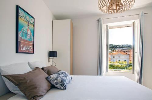 a bedroom with a white bed and a window at Totolulu Cannes Smart in Cannes