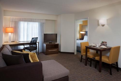 a hotel room with a couch and a table and a room at Cambridge Suites Mississauga in Mississauga