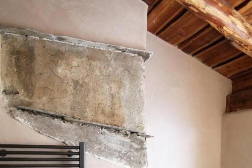 a stone wall in a room with a bench at Curt di Clement Eco Mobility Hotel in Tirano