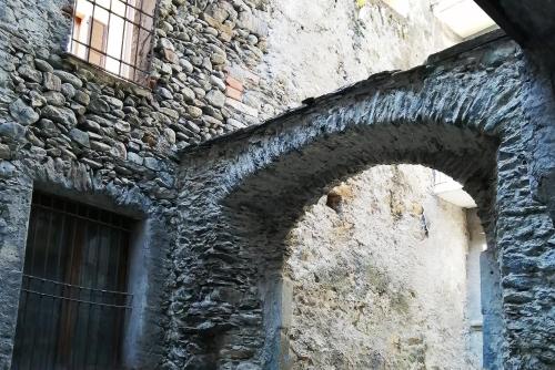 an old stone building with two windows and a door at Curt di Clement Eco Mobility Hotel in Tirano