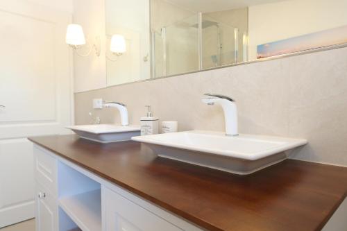 a bathroom with two sinks and two mirrors at Villa Ostseenordstern in Warnemünde