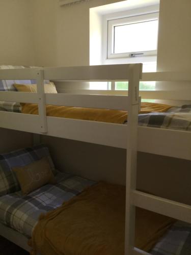 two bunk beds in a room with a window at Grooms cottage in Thornton