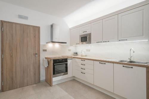 a kitchen with white cabinets and a sink at Penzion Dvojka in Velké Bílovice