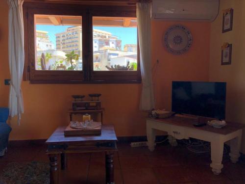 シャッカにあるCasa vacanze Sciaccaのリビングルーム(テレビ、テーブル、窓付)