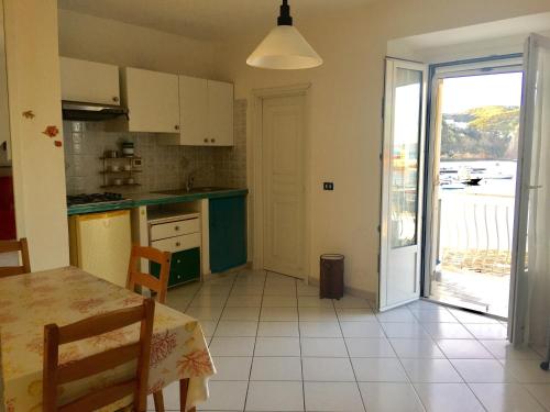 eine Küche mit einem Tisch und eine Tür zu einem Balkon in der Unterkunft Agenzia Isotur GINESTRA in Ponza