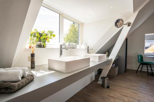 La salle de bains est pourvue d'un lavabo blanc et d'une fenêtre. dans l'établissement Gravenstraat, à Den Burg