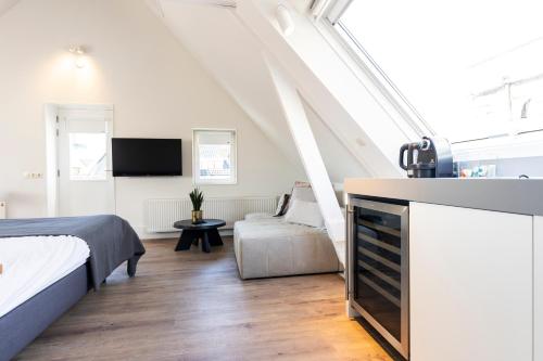 een slaapkamer met een bed en een tv en een bank bij Gravenstraat in Den Burg