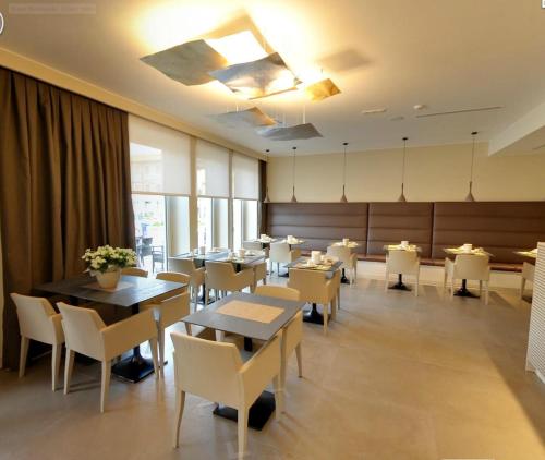 una sala da pranzo con tavoli e sedie bianche di Hotel Metropole a Grado