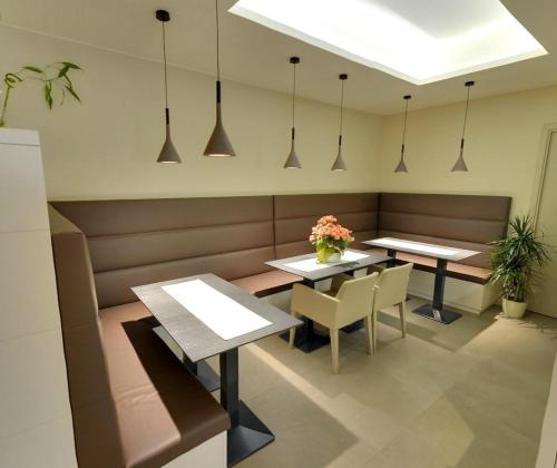 a restaurant with two tables and chairs and pendant lights at Hotel Metropole in Grado