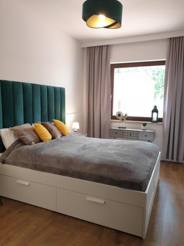 a bedroom with a large bed with a green headboard at Apartament MilioNova in Łódź