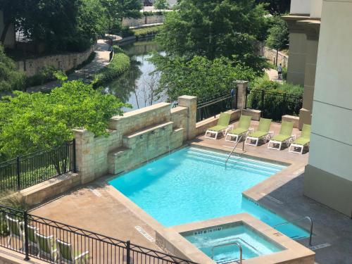 a swimming pool with a river in the background at Wyndham Garden River Walk Museum Reach in San Antonio