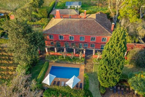 an aerial view of a large red house with a swimming pool at Quinta das Vinhas in Calheta