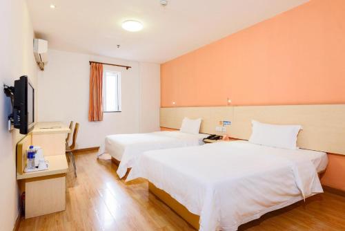 a hotel room with two beds and a flat screen tv at 7Days Inn Nanan Shuitou southeast Fortune Plaza in Quanzhou