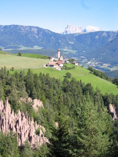 a house on top of a hill with trees and mountains at Sporthotel Spoegler in Collalbo