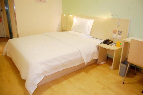 a bedroom with a large white bed and a telephone at 7Days Inn Qinhuangdao Railway Station in Qinhuangdao