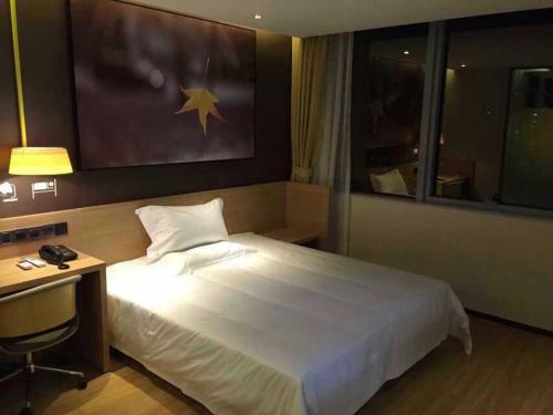 een slaapkamer met een groot wit bed en een bureau bij 7Days Inn Yueyang Pingjiang Tianyue Road Pedestrian Street in Pingkiang-hsien