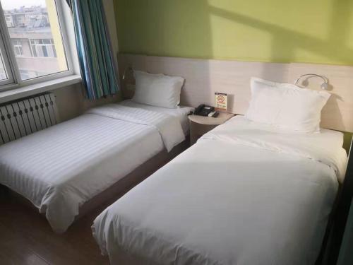 two beds in a small room with two windows at 7Days Inn Zhangjiakou Xuanhua Caishenmiao Street in Zhangjiakou