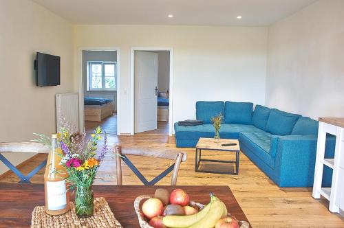 ein Wohnzimmer mit einem blauen Sofa und einem Tisch mit Obst in der Unterkunft Allgäu Ferienhof Schönberger in Argenbühl