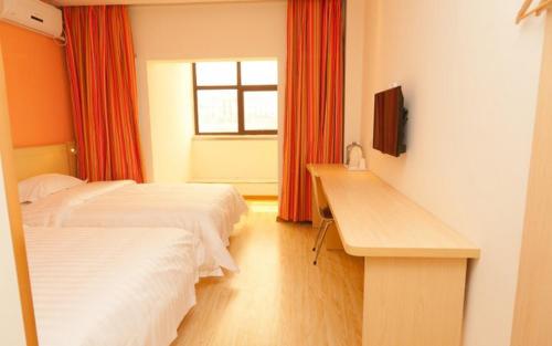 a room with two beds and a desk and a window at 7Days Inn Guangrao Bus Terminal in Dongying